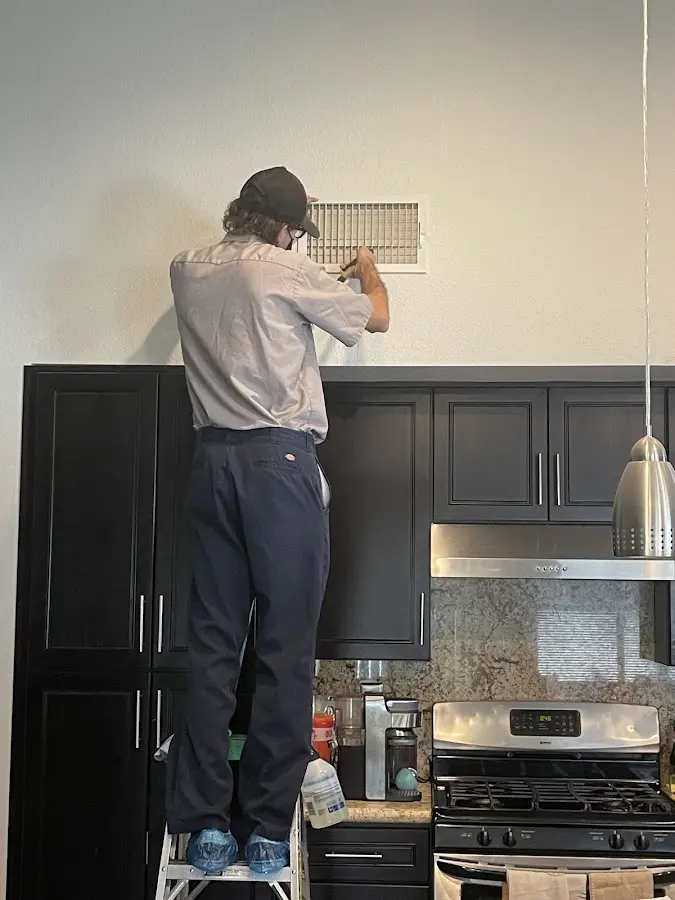Technician inspecting an air vent during HVAC service in Columbus